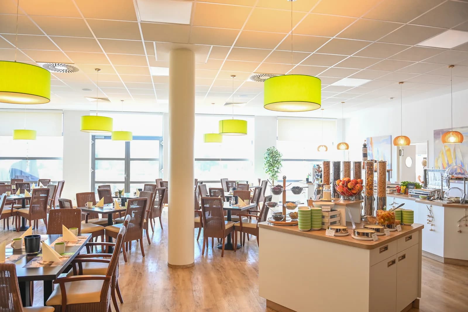 Lichte ontbijtruimte met buffet, houten tafels en groene hanglampen