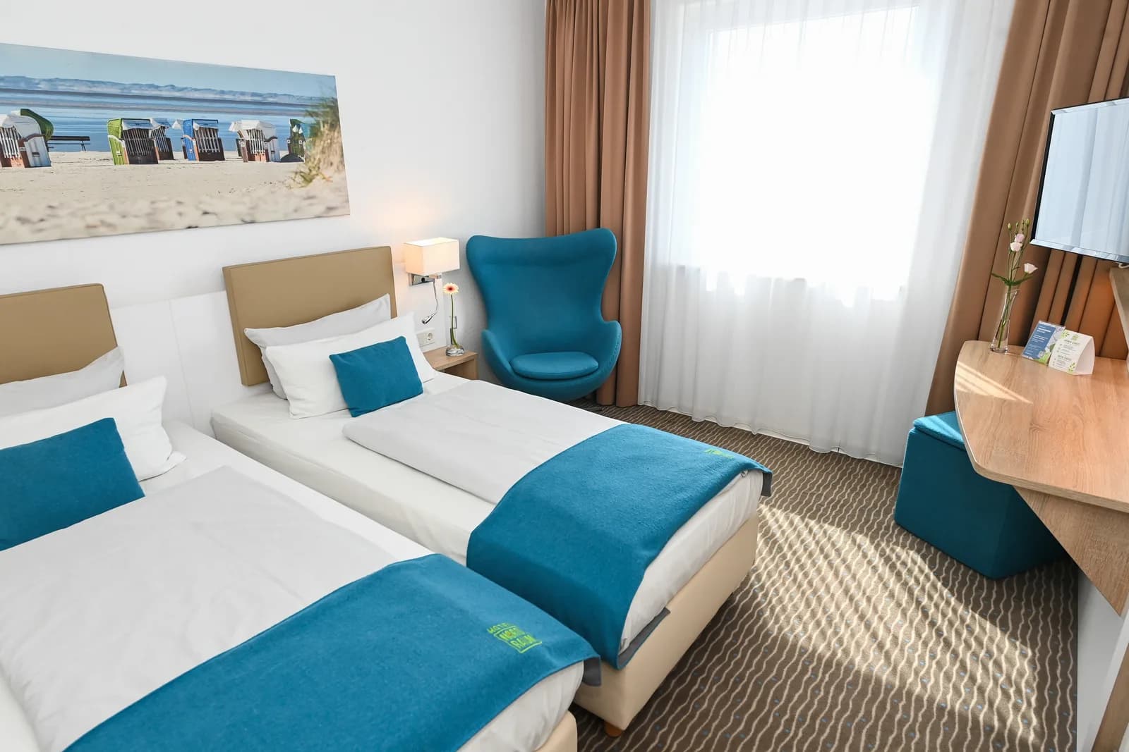 Chambre twin avec deux lits et fauteuil bleu