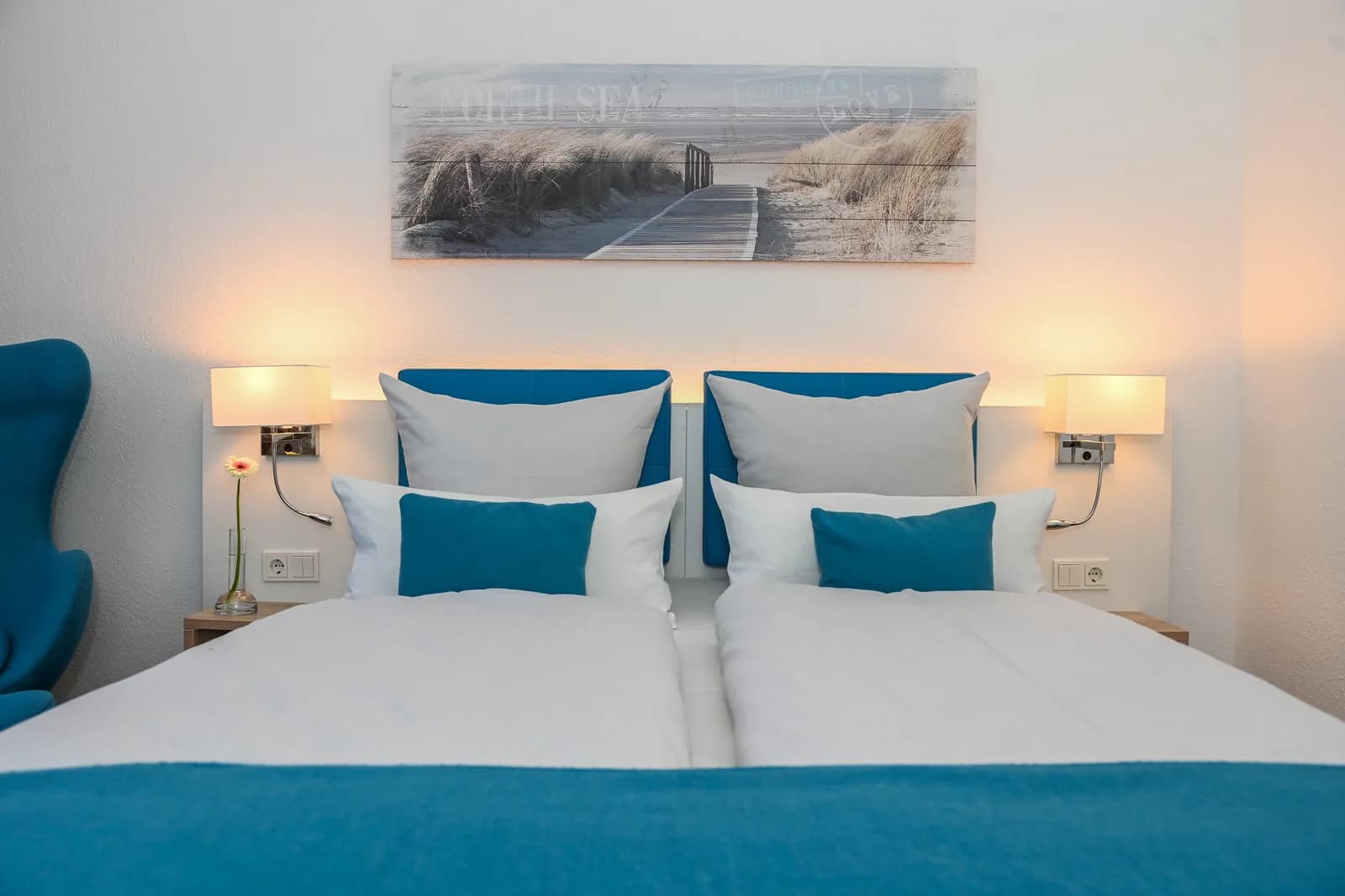 Zwei Betten nebeneinander mit blauen Kissen